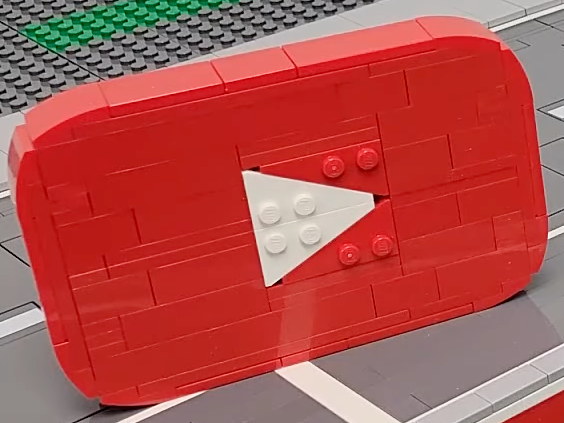 A screenshot of a LEGO-built YouTube logo, sitting in a LEGO cityscape